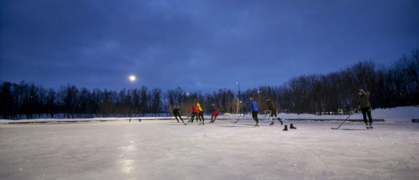 People on snowy field against sky during winter