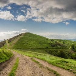 Road amidst green landscape against sky