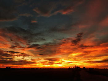 Scenic view of dramatic sky over silhouette landscape during sunset