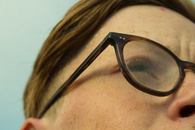 Close-up of woman wearing eyeglasses against white background