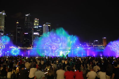 Crowd at night in city against sky