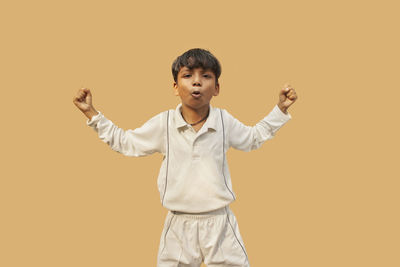 Portrait of boy standing against yellow background