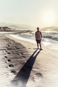 Full length of man standing on beach against sky