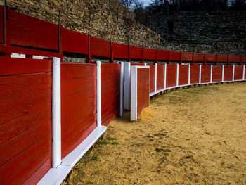 Empty footpath by red wall