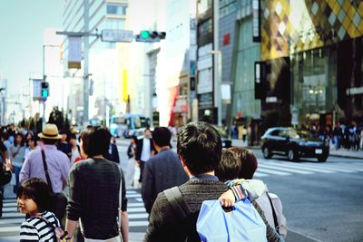 Rear view of people walking on street in city