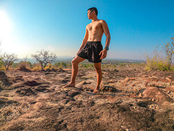 Full length of shirtless man standing on land against sky