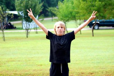 Portrait of boy gesturing peace sign on field