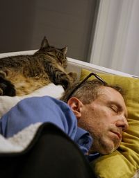 Man sleeping by cat on bed at home