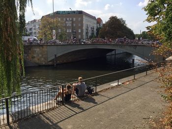 People on footbridge over river in city