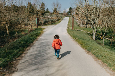 Rear view of chil walking on empty road