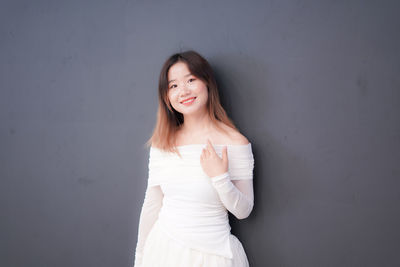 Portrait of young woman standing against curtain