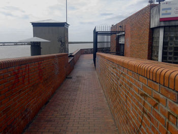 Narrow walkway along sea with buildings in background