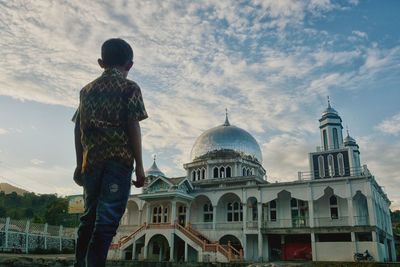 Man standing outside building against sky