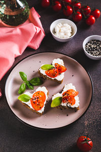Heart sandwiches with ricotta and tomatoes on rye bread on a plate vertical view