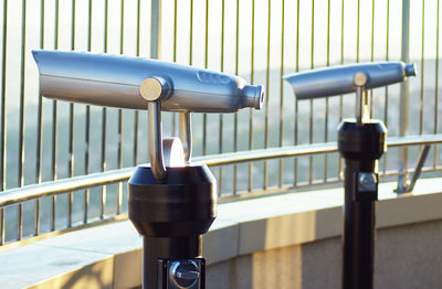 Close-up of coin-operated binoculars against railing