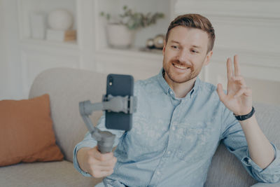 Portrait of smiling man holding camera at home