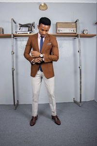 Full length portrait of young man standing against wall