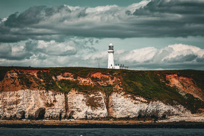 Lighthouse by sea against sky