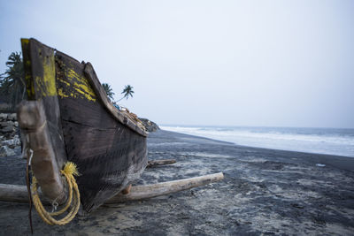 Fishing boat on shore at beach against sky