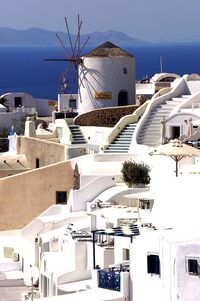 Traditional windmill and houses at santorini by aegean sea against sky