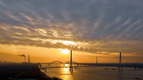 Bridge over sea against sky during sunset