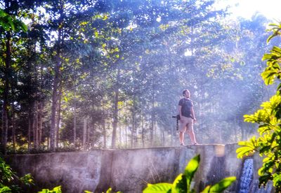 Woman standing by tree trunk