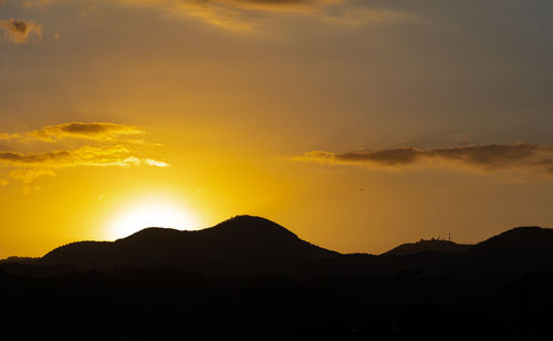 Scenic view of silhouette mountains against orange sky