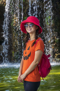 Portrait of smiling woman standing against waterfall