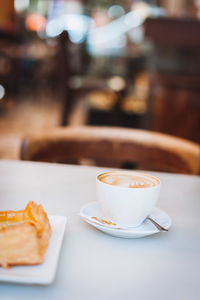 Cappuccino with snack served on table in cafe