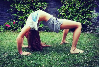 Full length of woman exercising on field in backyard