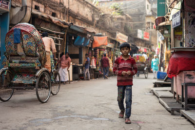 Rear view of people walking on street in city