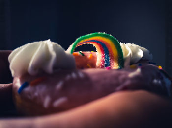 Close-up of hand holding ice cream cone against black background