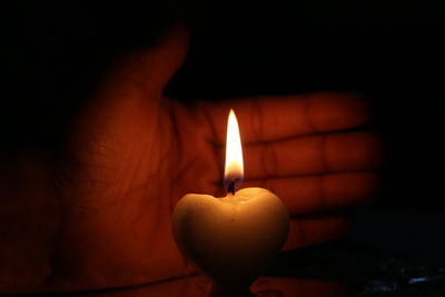 Close-up of lit candle in darkroom