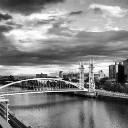 Bridge over river against cloudy sky