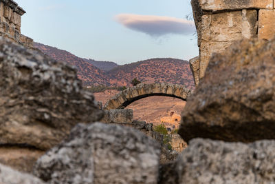 Stone wall by rocks against sky