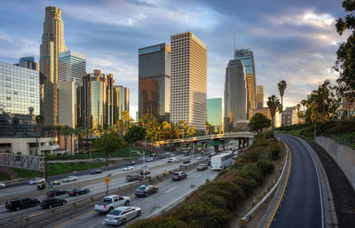 Vehicles on road amidst buildings in city against sky