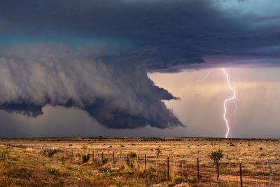 Panoramic view of lightning over landscape against storm clouds