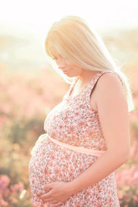 Smiling pregnant woman standing on field