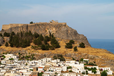 Scenic view at the city of lindos with white houses, the antique acropolis on top of the mountain