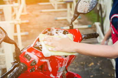 Midsection of woman washing motor scooter outdoors