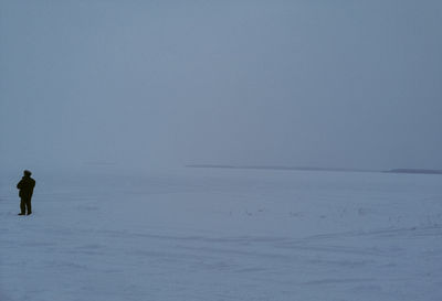 Person on snow covered land against sky