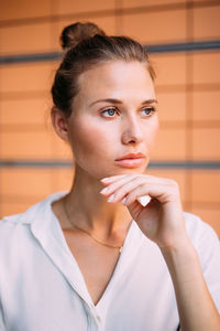 Beautiful young woman with hand on chin looking away