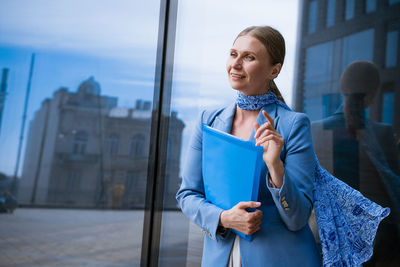 Business woman with folder in hand near office building