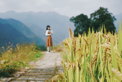 Woman standing on field against sky