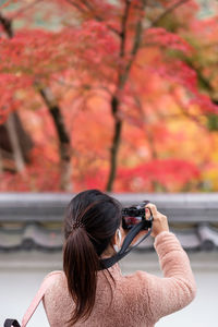 Rear view of woman photographing on camera