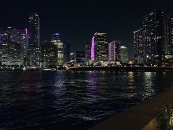 Illuminated modern buildings in city against sky at night