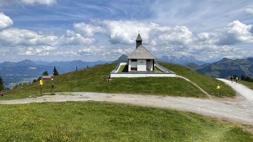 Church on grassy field by mountains against sky