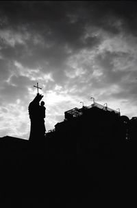 Low angle view of silhouette statue against cloudy sky