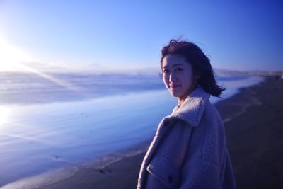 Young woman standing against sky during sunset