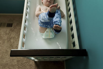 High angle view of boy wearing pant while lying on bunkbed